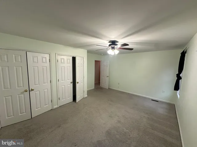 an empty room with a chandelier fan and a window