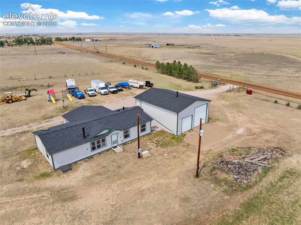 1350 South Calhan Highway Yoder, CO 80864 - Photo 3 of 45 Single-story residence with a dark shingle roof and light-colored siding, accompanied by a detached two-bay garage