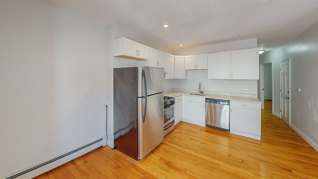 67 Marion Street, Unit 2 Boston, MA 02128 - Photo 3 of 15 a kitchen with white cabinets and wooden floor