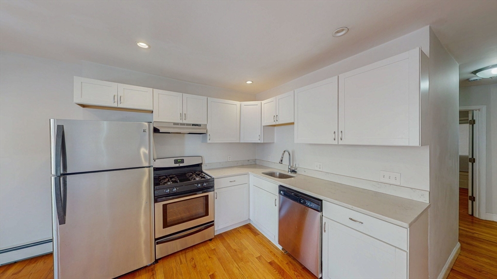 67 Marion Street, Unit 2 Boston, MA 02128 - Photo 4 of 15 a kitchen with a refrigerator a stove top oven and cabinets