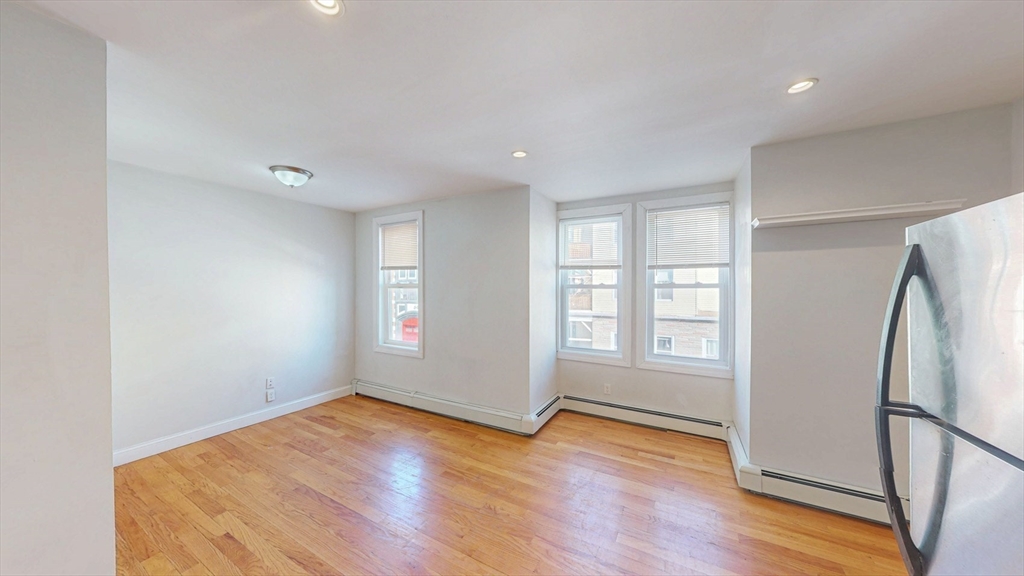 67 Marion Street, Unit 2 Boston, MA 02128 - Photo 5 of 15 an empty room with wooden floor and a window