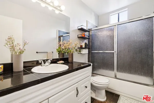 a bathroom with a granite countertop sink toilet and shower