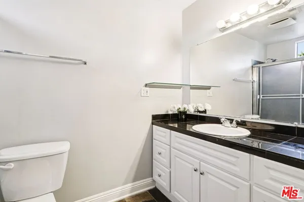 a bathroom with a granite countertop sink a toilet and a mirror