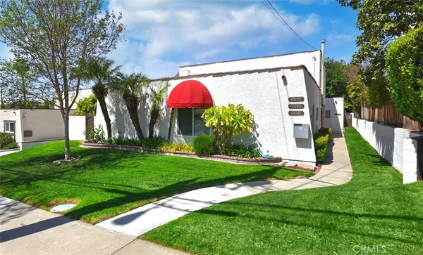 a view of a small yard in front of a house with plants and large tree