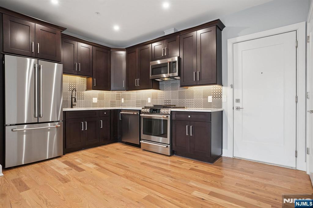 108 Montgomery Street Bloomfield, NJ 07003 - Photo 6 of 31 a kitchen with stainless steel appliances granite countertop a stove a refrigerator and a sink with wooden floor