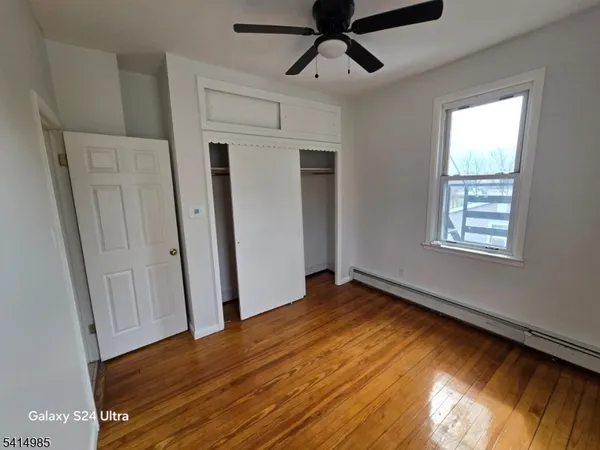 a view of empty room with wooden floor and fan