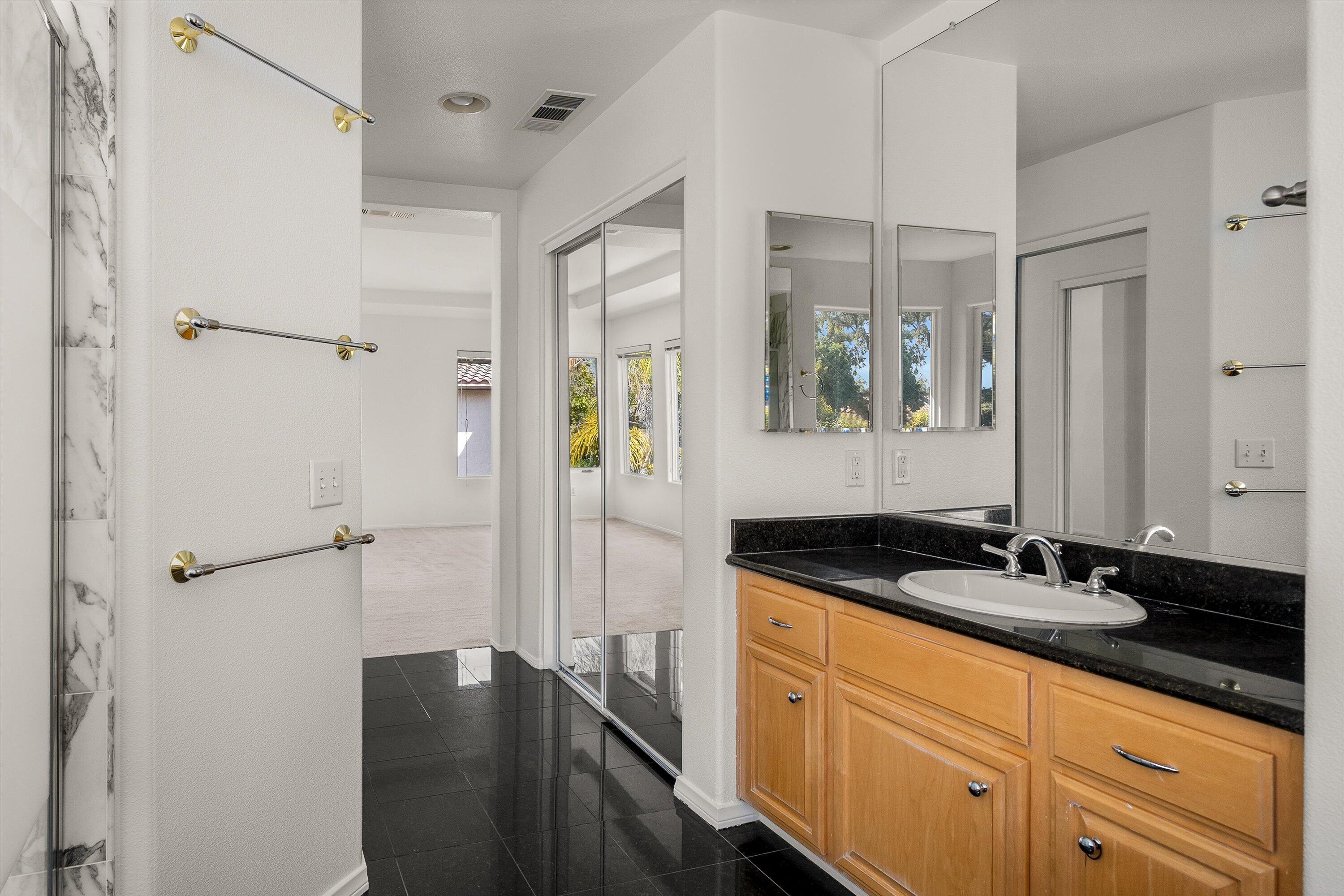 458 Greenleaf Court Goleta, CA 93117 - Photo 16 of 34 a bathroom with a granite countertop sink a mirror a vanity and a shower