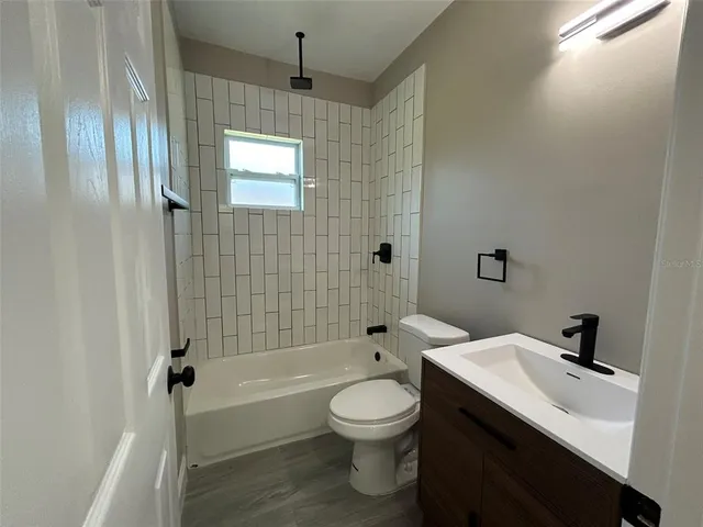 a bathroom with a bathtub shower sink mirror and toilet