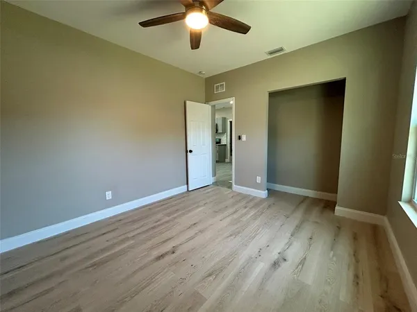 an empty room with wooden floor and a ceiling fan