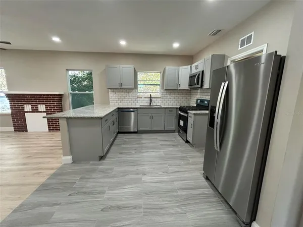a kitchen with stainless steel appliances granite countertop a refrigerator stove top oven and sink