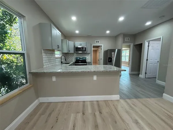 a view of kitchen with granite countertop cabinets wooden floor and a window