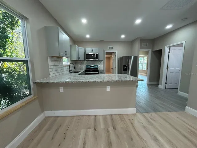 a view of kitchen with granite countertop cabinets wooden floor and a window