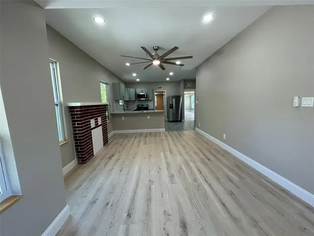 an empty room with wooden floor a ceiling fan and staircase