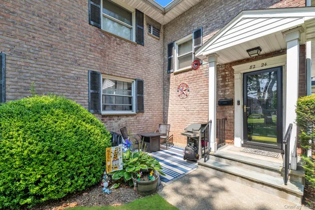 a view of a brick house with potted plants and a table and chairs