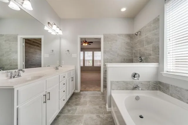 a bathroom with a tub a double vanity sink and mirror