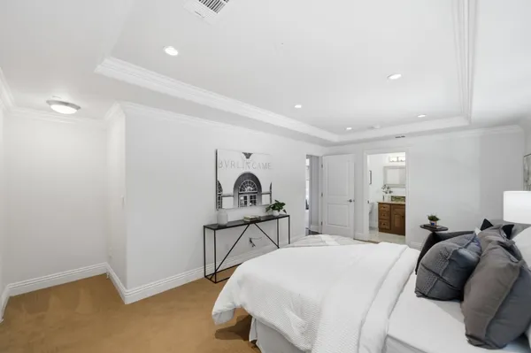 a bedroom with a bed and a lamp on dresser with wooden floor