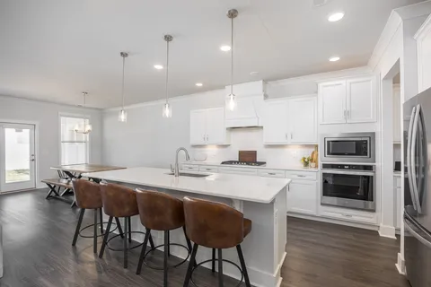 a kitchen with stainless steel appliances granite countertop a stove a sink a refrigerator a microwave oven with a dining table and chairs