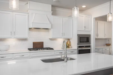 a kitchen with granite countertop a stove and a white cabinets