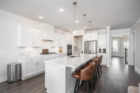 a large kitchen with kitchen island a dining table chairs and white cabinets