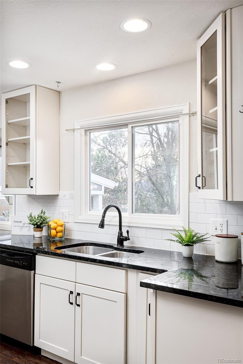 13492 Jackson Drive Thornton, CO 80241 - Photo 8 of 25 a kitchen with stainless steel appliances white cabinets a window and a kitchen island