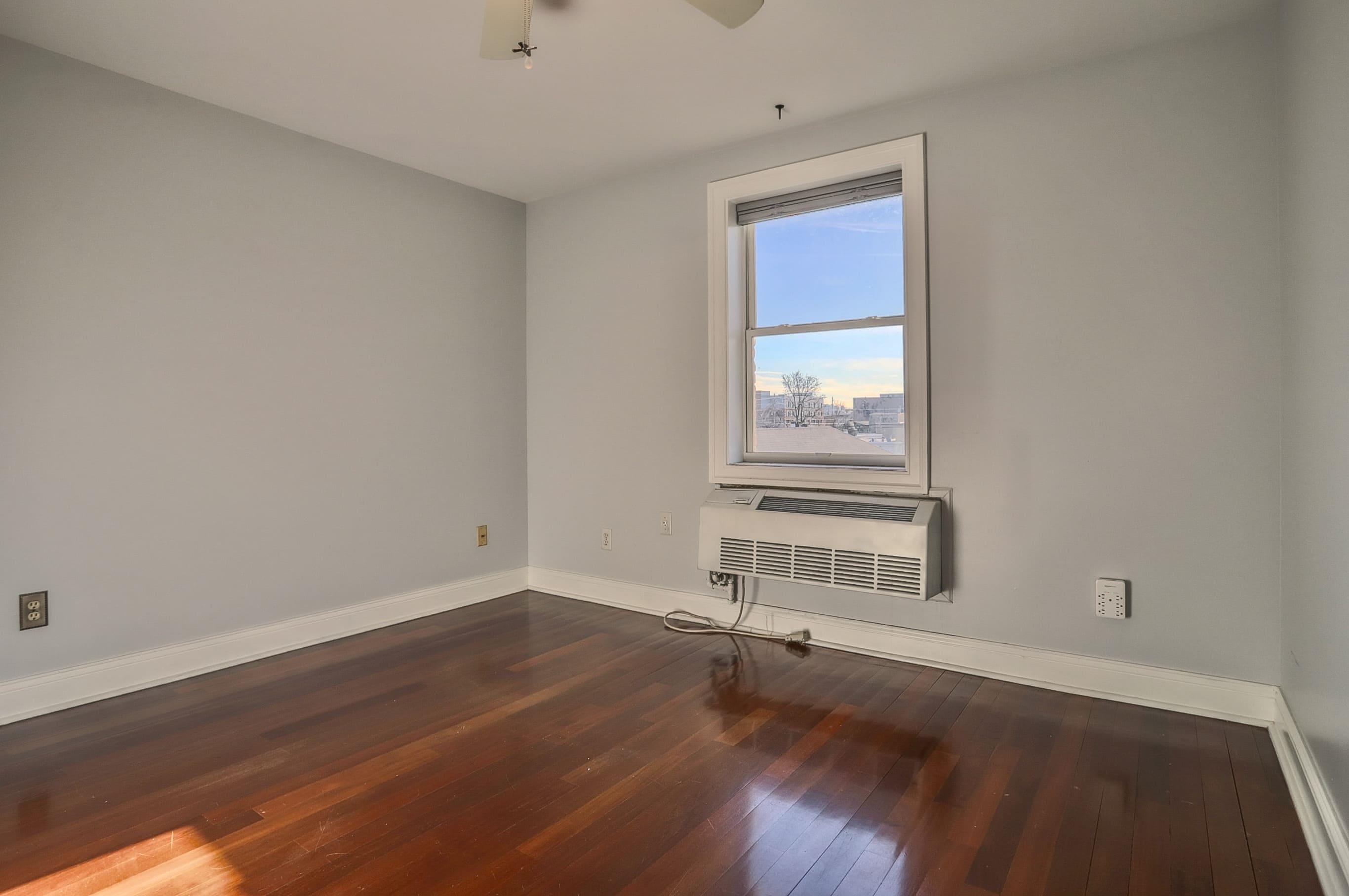 1720 New York Avenue, Unit 406 Union City, NJ 07087 - Photo 17 of 21 an empty room with wooden floor and windows