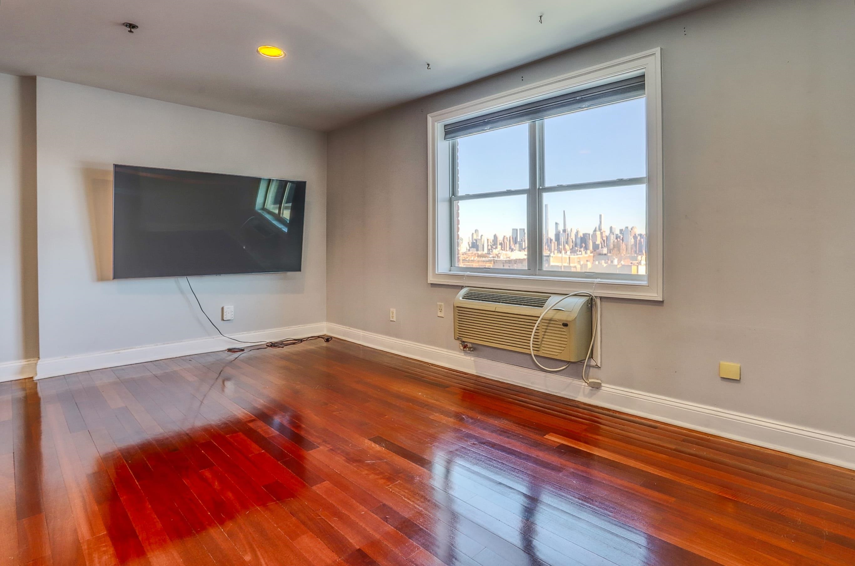 1720 New York Avenue, Unit 406 Union City, NJ 07087 - Photo 6 of 21 a view of an empty room with wooden floor and a window
