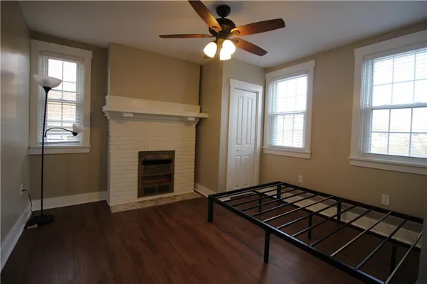 an empty room with wooden floor fireplace and windows