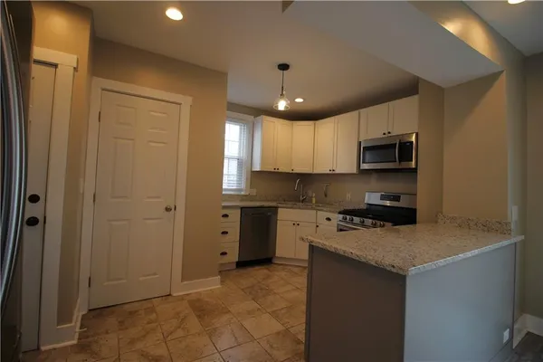 a kitchen with stainless steel appliances granite countertop a stove a sink and a refrigerator