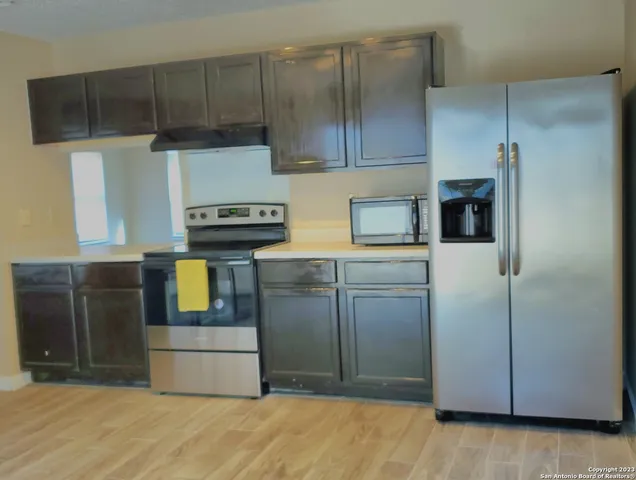 a kitchen with stainless steel appliances kitchen island granite countertop a refrigerator a stove and a sink