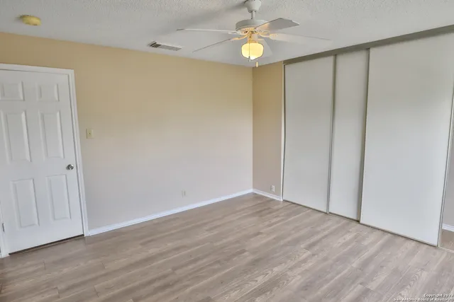 an empty room with wooden floor and windows