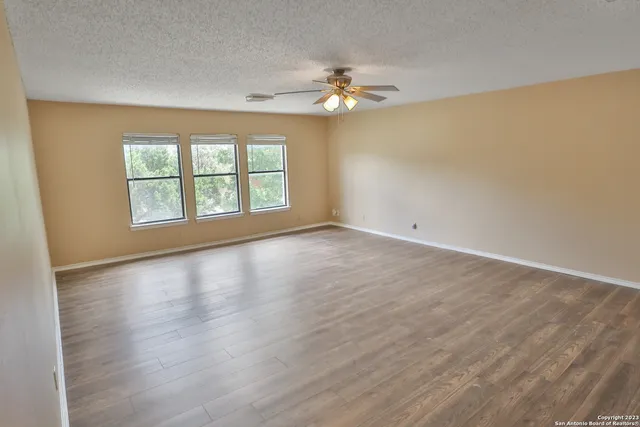 a view of empty room with wooden floor and fan