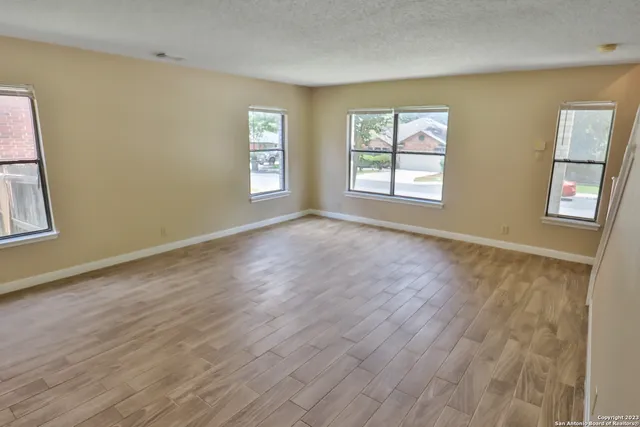 a view of an empty room with a window and wooden floor