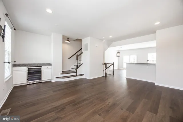 a view of empty room with wooden floor and kitchen