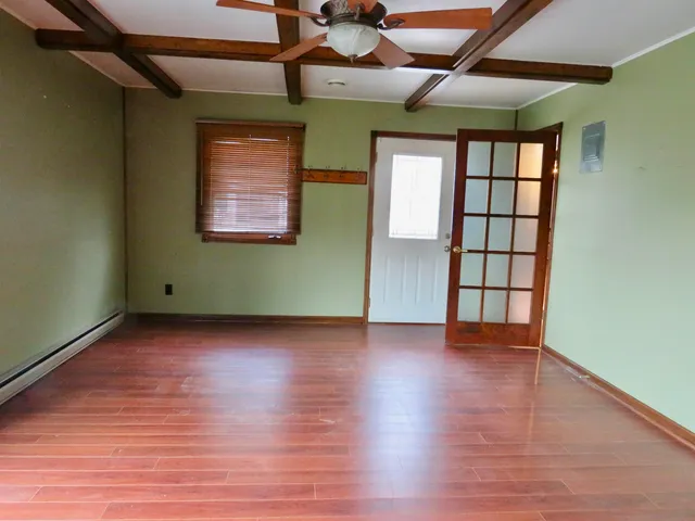an empty room with a ceiling fan and wooden floor
