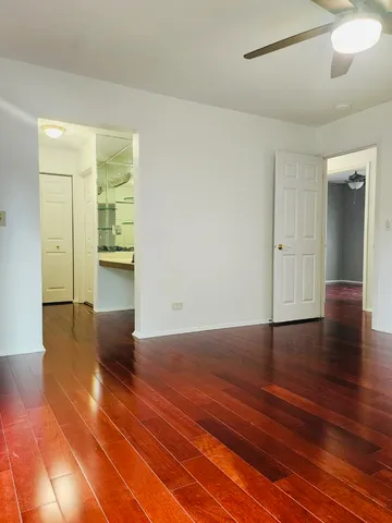 a view of a hallway with wooden floor and a bathroom