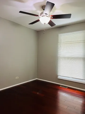 an empty room with wooden floor fan and window