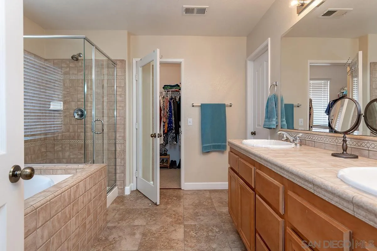304 River Ranch Way Oceanside, CA 92057 - Photo 30 of 44 a bathroom with a granite countertop sink a mirror a bathtub and shower