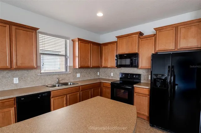 a kitchen with stainless steel appliances granite countertop a refrigerator a sink a stove a microwave and wooden cabinets