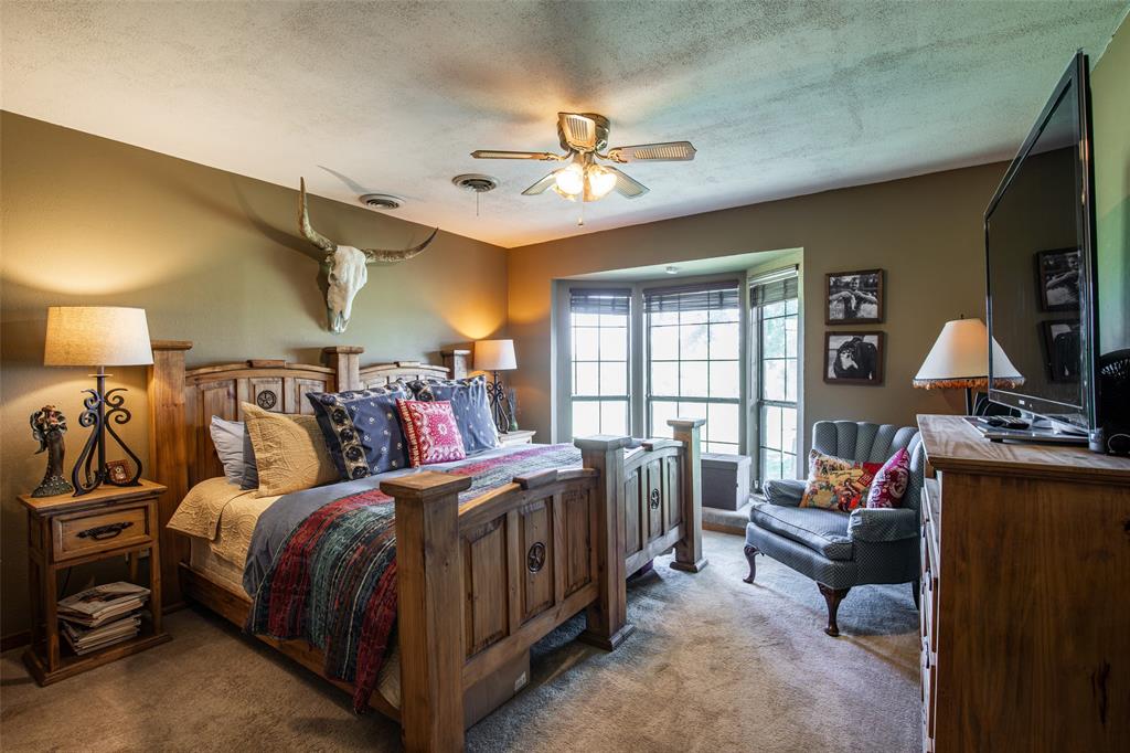 2043 Huddleston Road Sunset, TX 76270 - Photo 17 of 36 a bedroom with a bed a couch and dresser with wooden floor