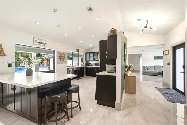 a kitchen with stainless steel appliances kitchen island granite countertop a table chairs and a refrigerator