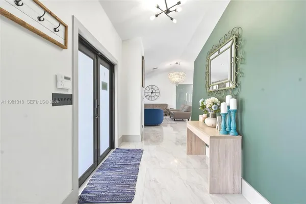 a hallway with a dining table a chandelier and a rug