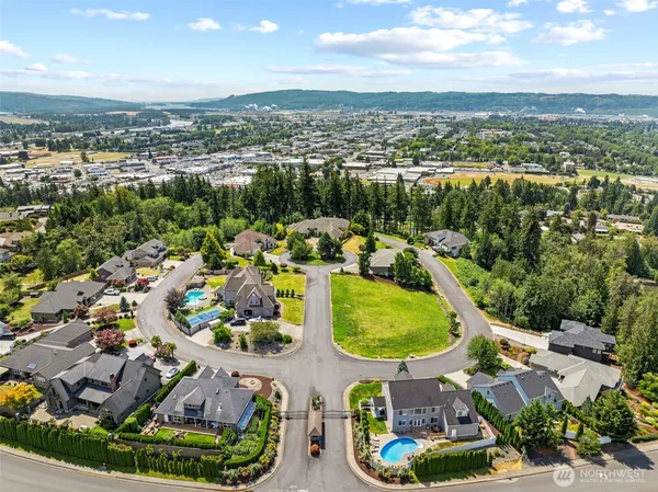 an aerial view of a residential houses with outdoor space and a lake view in back