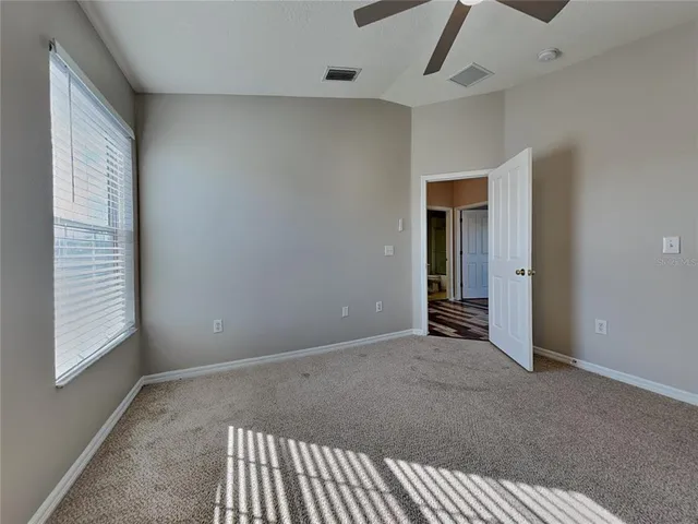 an empty room with chandelier fan and windows