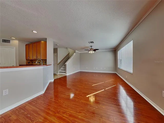 a view of empty room with wooden floor and fan