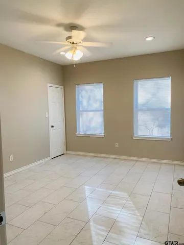 an empty room with windows and chandelier fan