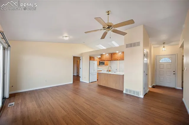 a view of a hallway with wooden floor and a kitchen