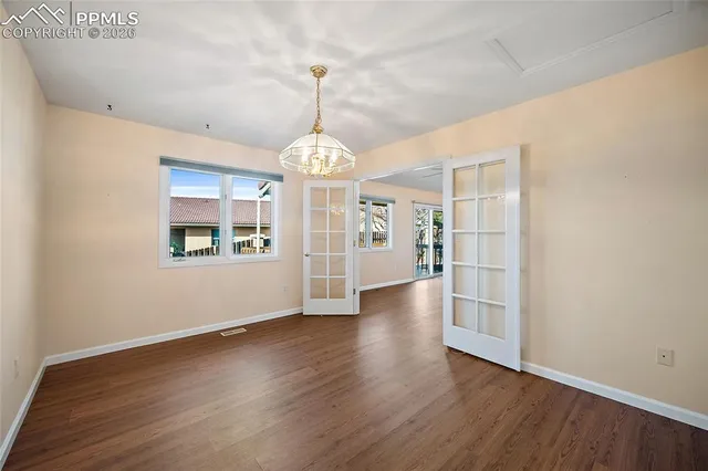 a view of an empty room with window and wooden floor