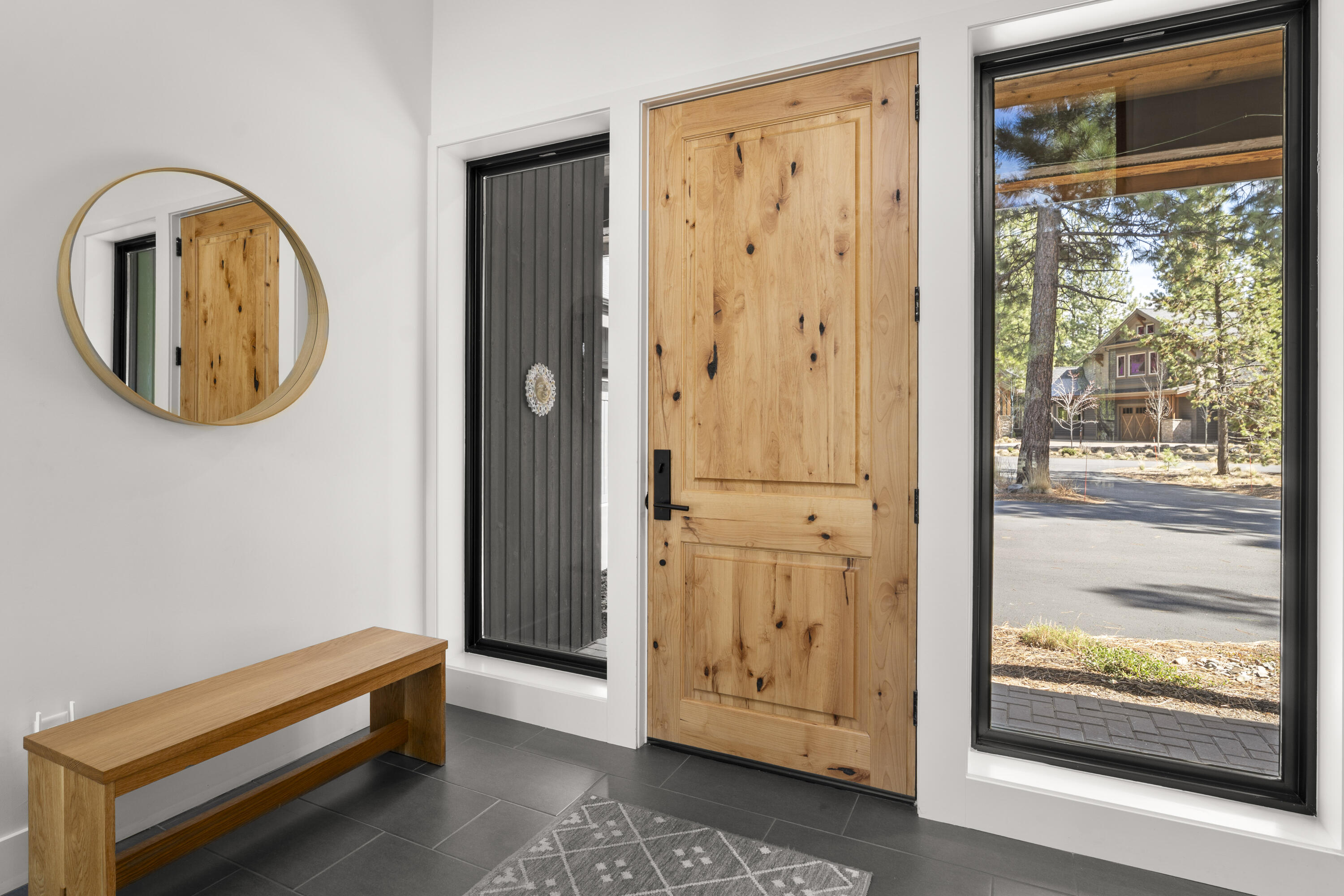 56670 Sunstone Loop, Unit LOT 141 Bend, OR 97707 - Photo 10 of 62 Bright and welcoming entry foyer featuring a natural wood front door, vaulted ceiling, tile floors, and a simple modern palette. The covered paver entry offers both shelter and a strong architectural arrival.