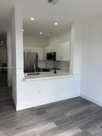 a view of kitchen with stainless steel appliances refrigerator stove microwave and cabinets