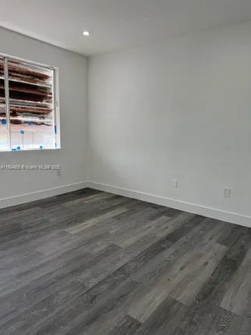 an empty room with wooden floor and window